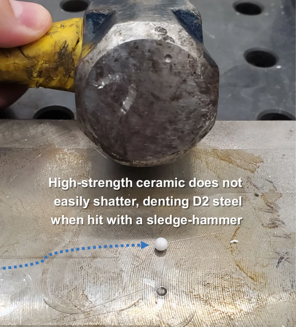 A technical ceramic part on a D2 steel block after being struck with a sledge-hammer, showing the steel dented rather than the ceramic shattered